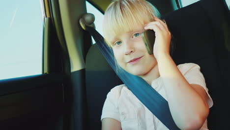 funny girl 6 years old speaks on the phone rides in the back seat of the car it is fastened with a s