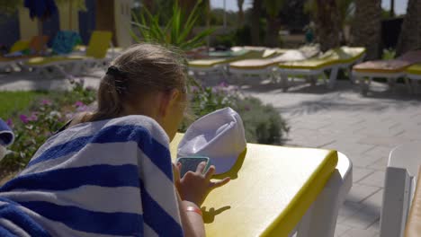 girl teenager typing message on mobile phone during sunbath on chaise longue