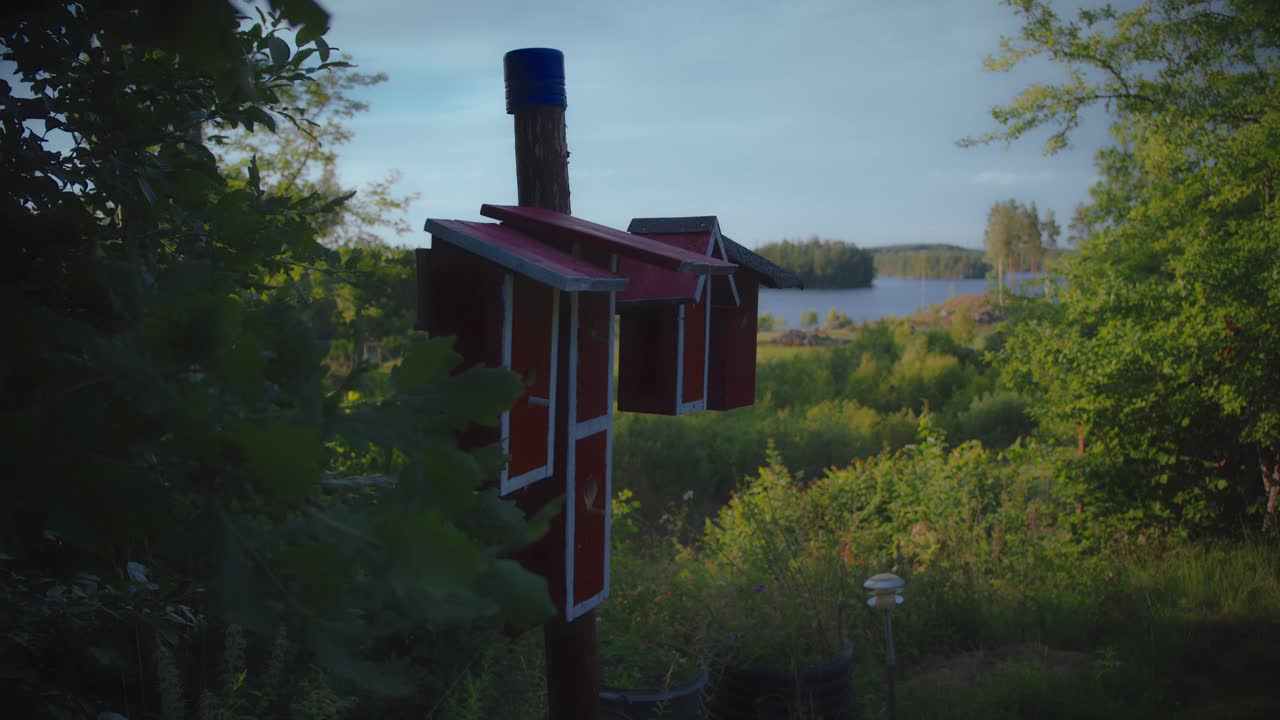 Casetta per uccelli rossa fatta in casa in un giardino accanto a un lago in Svezia