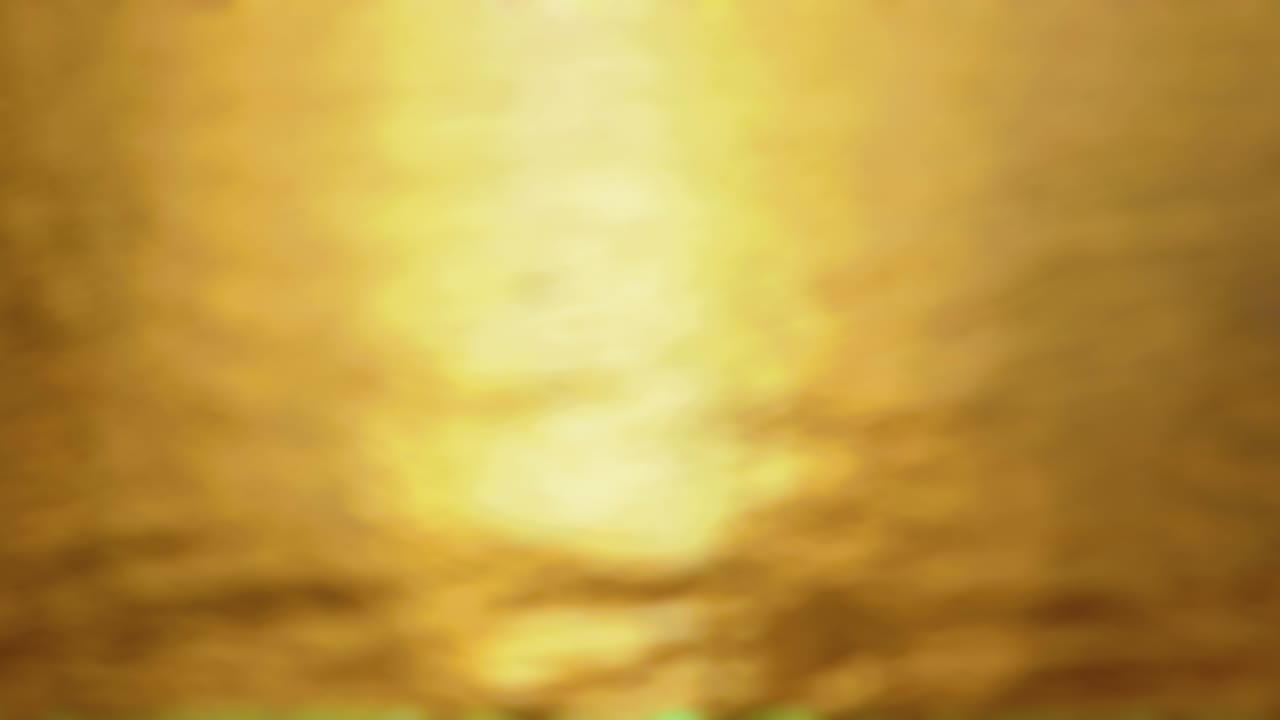 puesta de sol - bucle sin costuras de una toma de 4k completamente desfocada de una superficie de agua ligeramente ondulada. el sol está bajo y la luz reflejada brilla en la superficie del agua