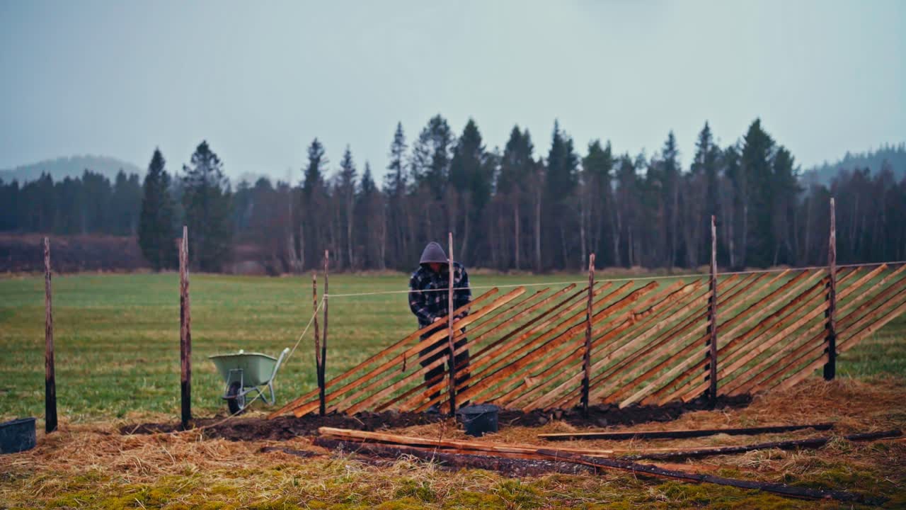 Man Building A Traditional Norwegian Skigard Fence With Slanting Rails. - timelapse shot