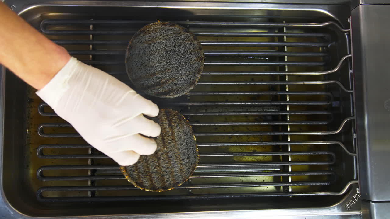 Grilled buns for hamburgers on the grill. Grilled brown bread. Barbecue. Delicious tasty dish on grid. Video from the top.