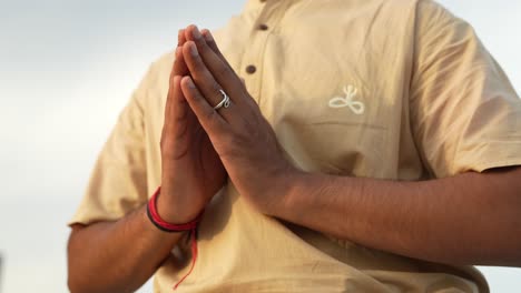 hombre indio irreconocible poniendo sus manos juntas mientras hace una postura de hatha yoga en el sol de la mañana al amanecer