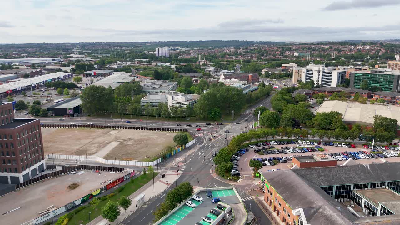 Drone footage pans over a modern urban park and business district in Leeds, England, under daylight with clear skies and steady camera movement