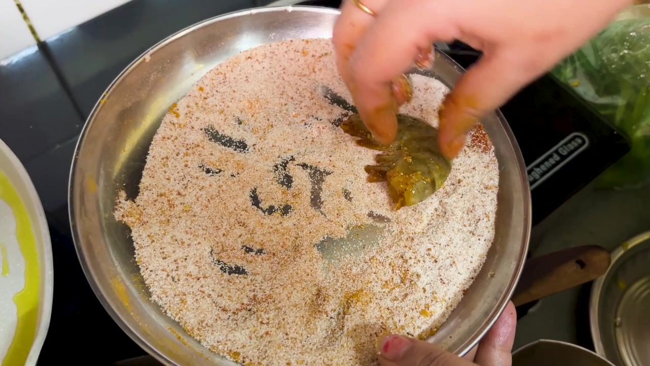 Empanando camarões marinados com farinha de rosca temperada antes de fritar na frigideira em casa.