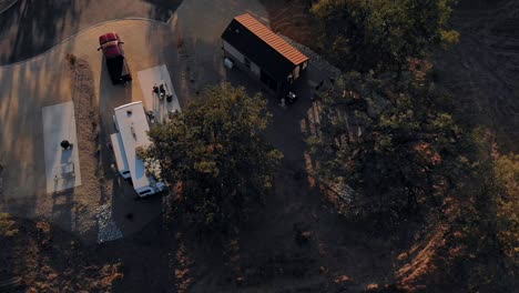 aerial pull back shot of an rv trailer in an rv park at sunset showing the setting sun.