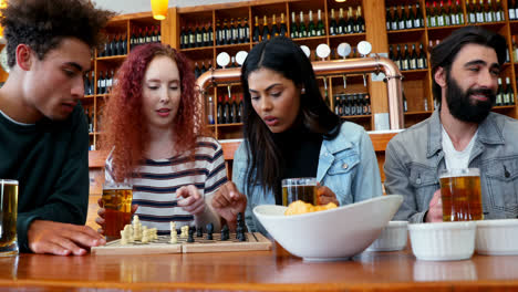 friends playing chess while having glass of beer in bar 4k