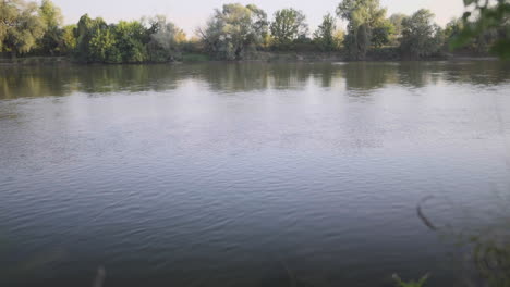 4k a tranquil river scene captured at dusk, featuring a calm water surface reflecting the soft hues of the sky