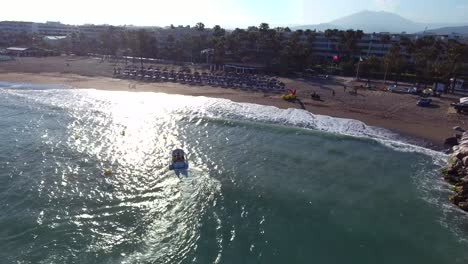 small-boat-coming-to-shore-during-a-sunset-filmed-from-drone-in-4k-in-marbella,-malaga-spain