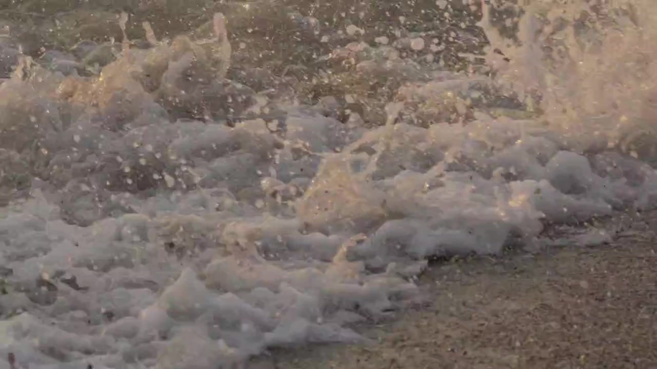 Closeup Sea Wave Foam, Water Spray on Sand Shore Detail Shimmering Golden Sunset