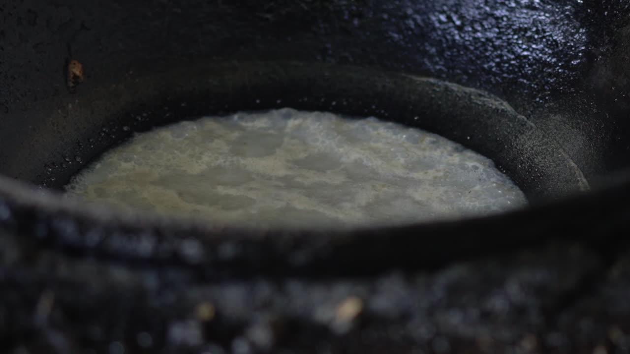 closeup of boiling fat in a black pot