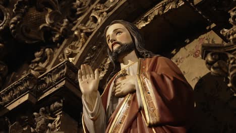 close up of jesus statue with raised hand and heart in ornate setting