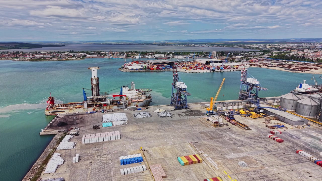 L'area portuale mostra banchine affollate e navi da carico in attività.