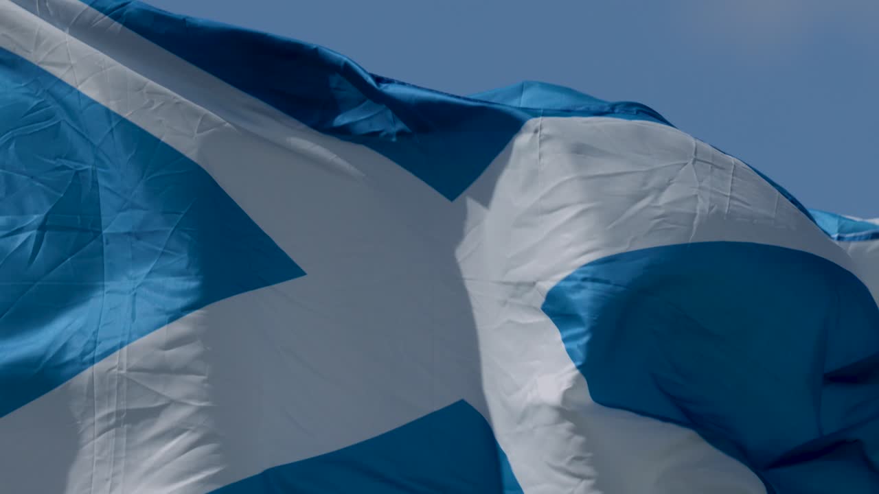 Blue and white flag ripples dynamically outdoors, bright daylight, close-up, steady camera, natural movement