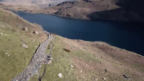 aerial video diving down the rocky face of the mountain toward to the blue river