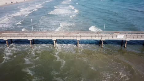 drone aerial view of the bob hall pier and waves at nueces county coastal park on north padre island, texas