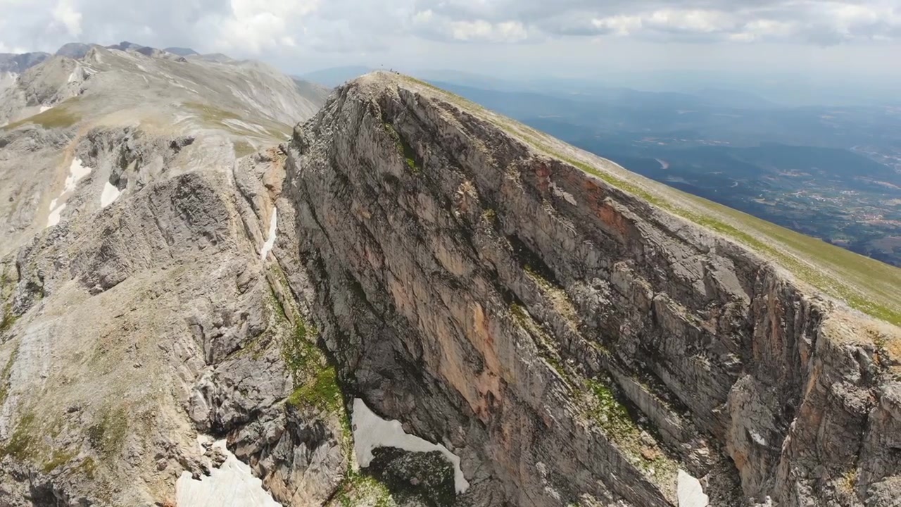 Vista aérea de un majestuoso pico rocoso de montaña con parches de nieve