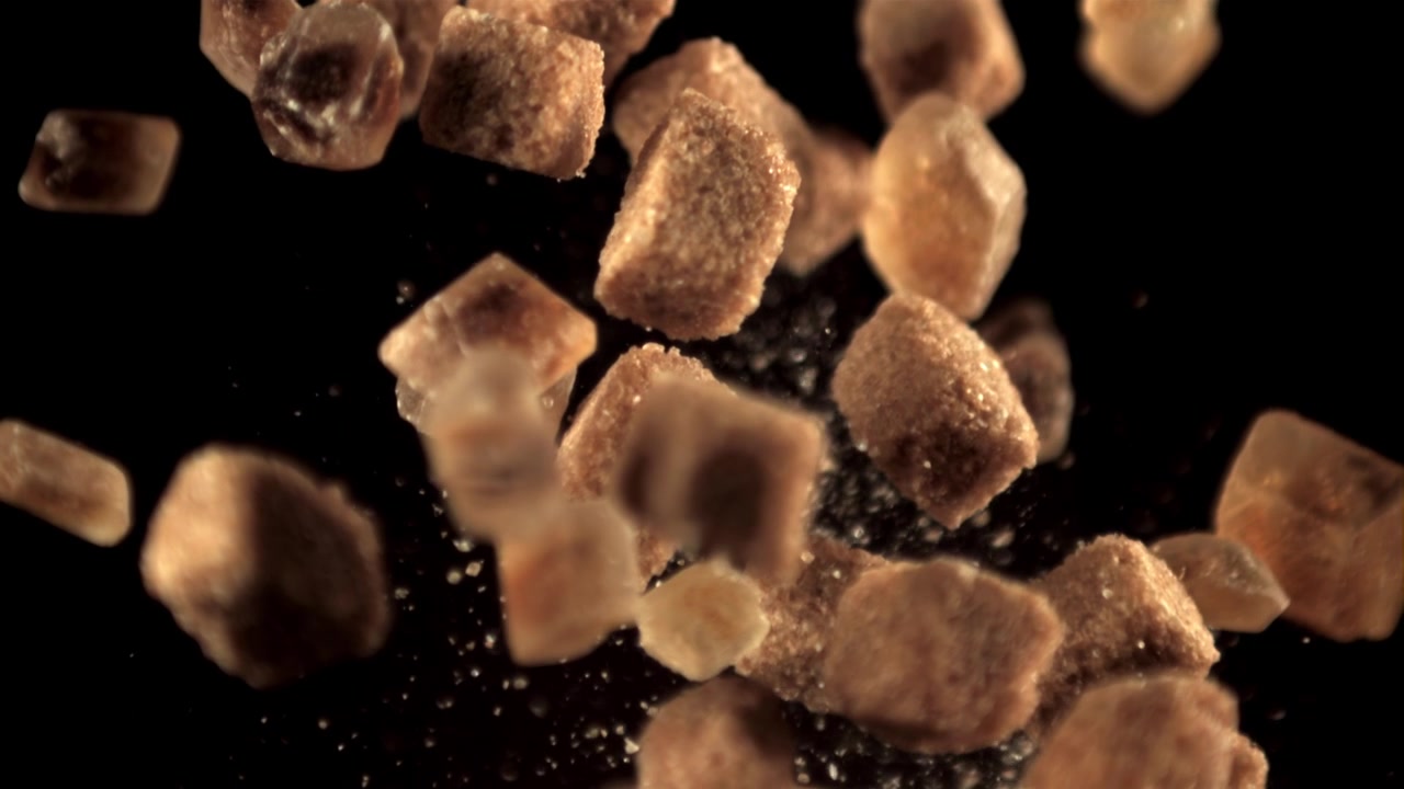Brown Sugar Cubes Falling in Slow Motion on Black Background
