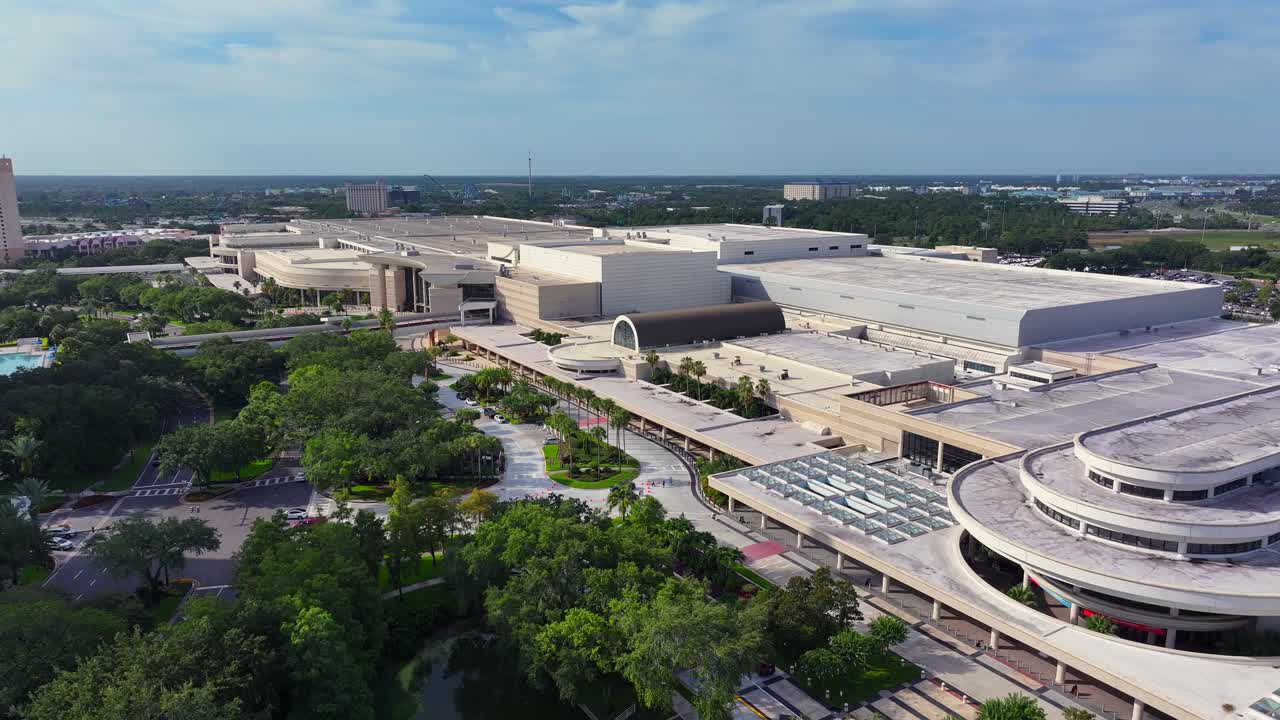 Fountain of lake in front of modern Icon Park and Convention Center in Orlando City, USA. Sunny day with modern buildings and neat park area. Florida, America.