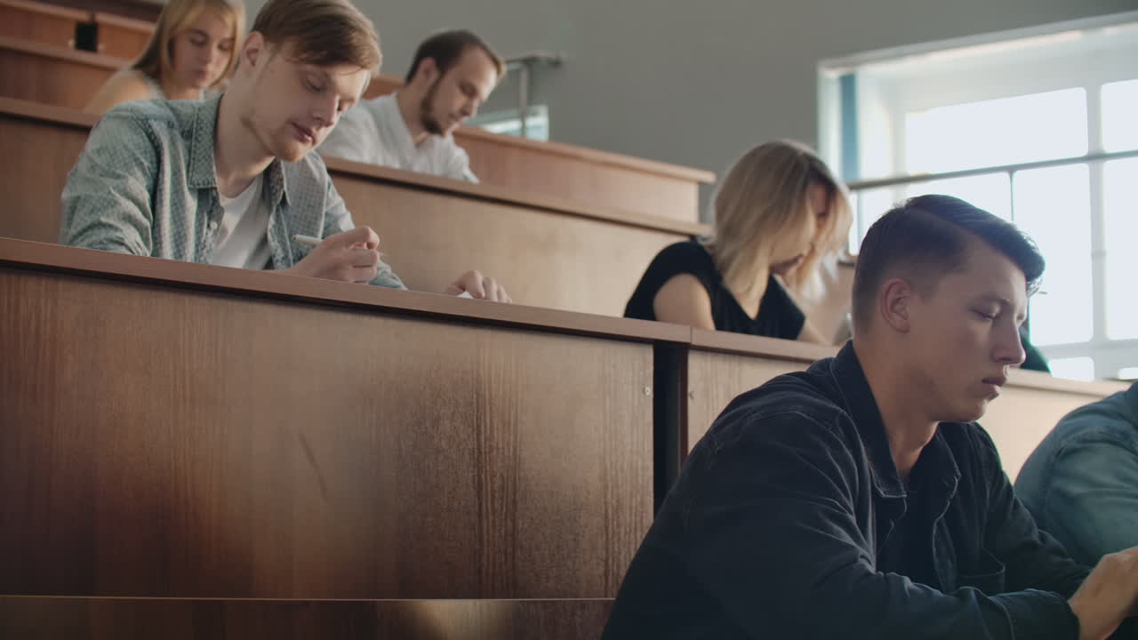 대규모 대학 수업에서 성공한 젊은 학생들은 강의를 듣고 녹음합니다.