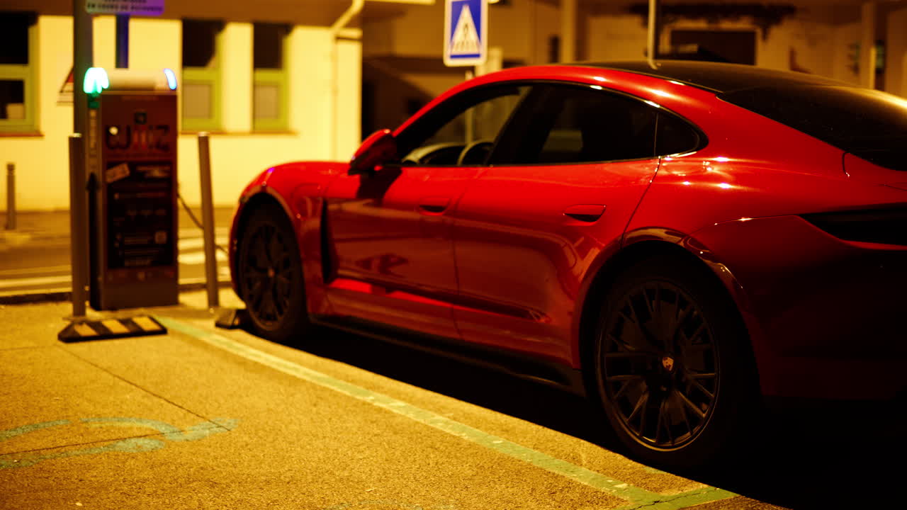 Aargau, Switzerland - September 14, 2024: Red Porsche Taycan charging on the street at night