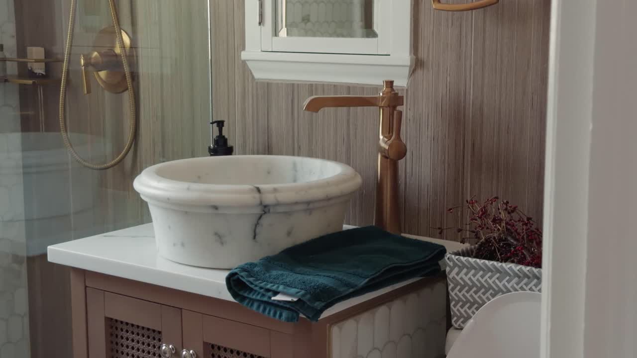 Sağdan sola kaydırma, modern bir banyoda mermer lavabo ve bakır musluğu ortaya çıkarıyor.