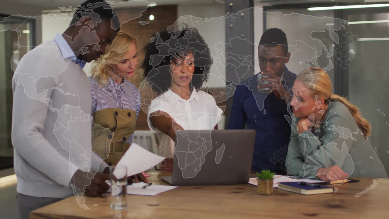 Diverse team collaborating over laptop with world map animation overlay
