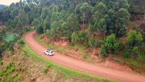 Geländewagen-Fährt-Auf-Unbefestigter-Straße-Am-Berg-Mit-Wald-In-Uganda,-Afrika