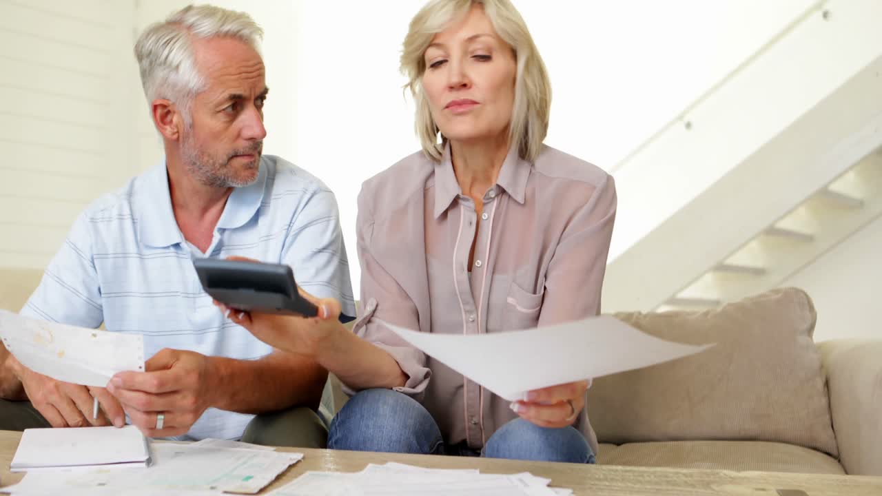 pareja estresada trabajando en sus cuentas en el sofá