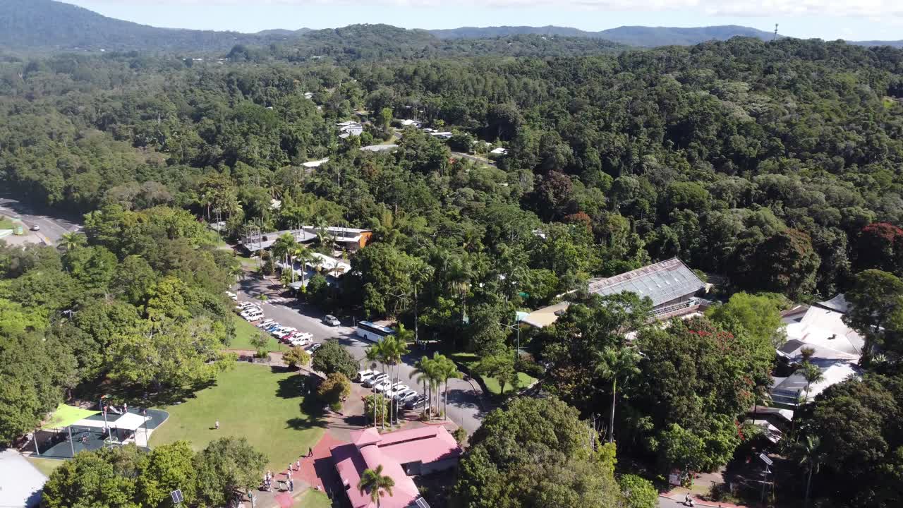 Drone ascending over a small mountain village surrounded by a tropical rainforest in North Queensland, Australia