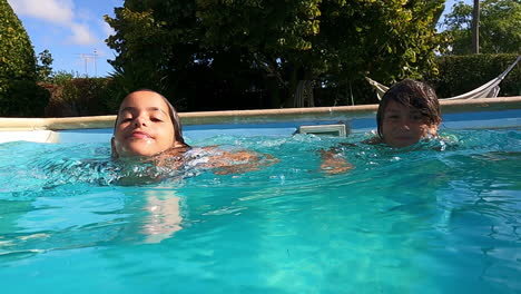 closeup of boy and girl swimming in pool on sunny day.