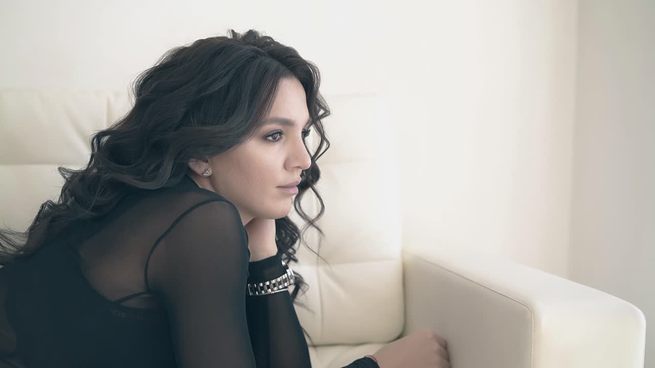 아름다운 갈색 여성이 큰 소파에 누워서 멀리 보입니다.