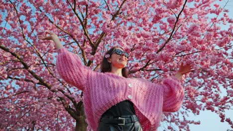 girl in soft pink sweater enjoying springtime cherry blossoms at sunset in europe