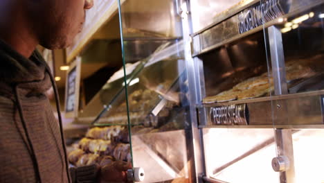 Man-selecting-cooked-mutton-and-chicken-steak-in-display