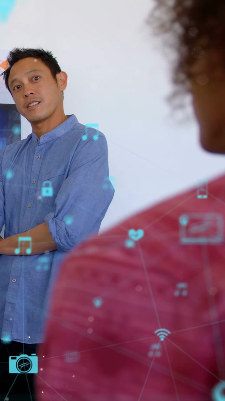 Man in blue shirt speaking to peer, cyan icons emerging, drifting between, clearing, showing tech