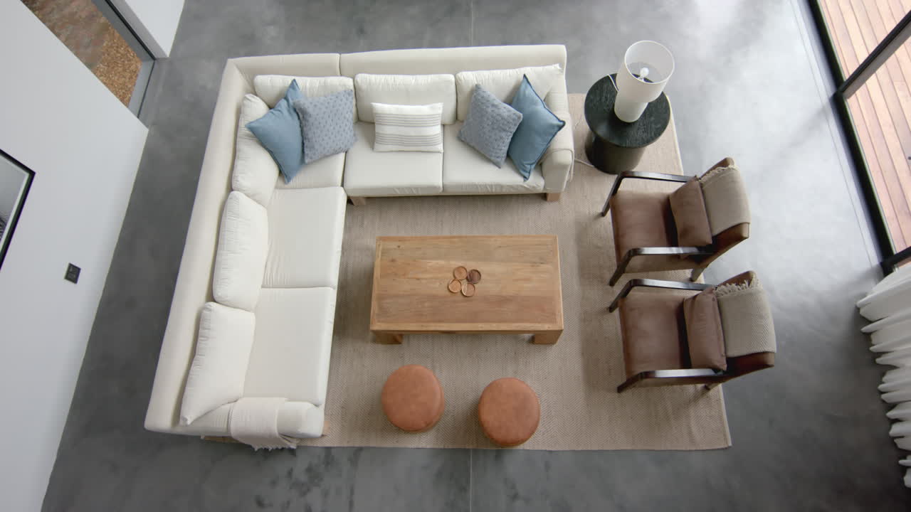 High angle view of couch and chairs in living room with doors to terrace, copy space, slow motion