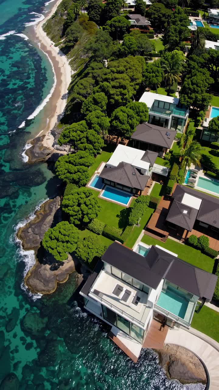 Aerial video view of luxury coastal homes with lush greenery and turquoise waters, showcasing modern
