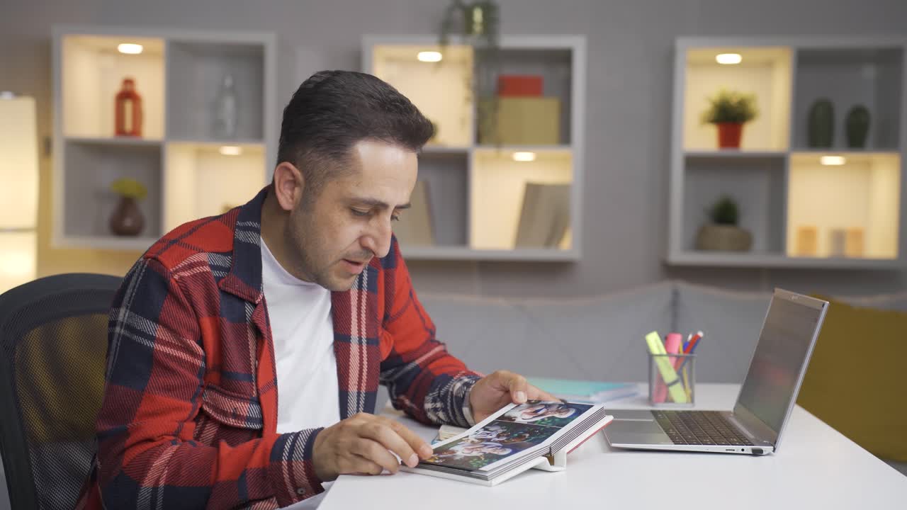 hombre mirando el álbum de familia con la mano temblorosa.
