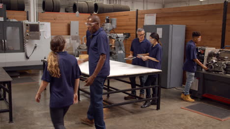 engineers working on machines in busy metal workshop