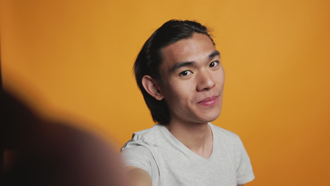 POV of asian smiling man taking pictures on camera