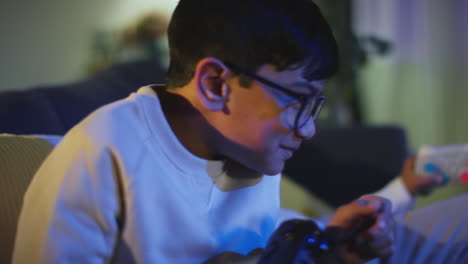 close up of young boy at home celebrating playing with computer games console on tv holding controllers late at night 1