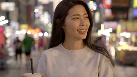 young woman enjoy bubble milk tea with street food in  night market