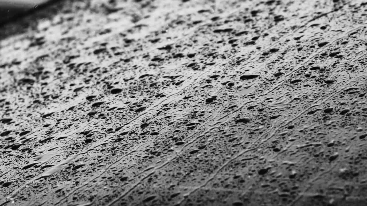폭풍우가 몰아치는 동안 차창 아래로 굴러 떨어지는 빗방울의 클로즈업 영상