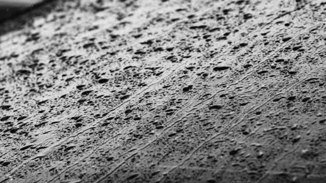 close up footage of raindrops rolling down a car window during a rainstorm