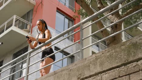 Low-angle-view-of-young-African-American-woman-using-mobile-phone-in-the-city-4k