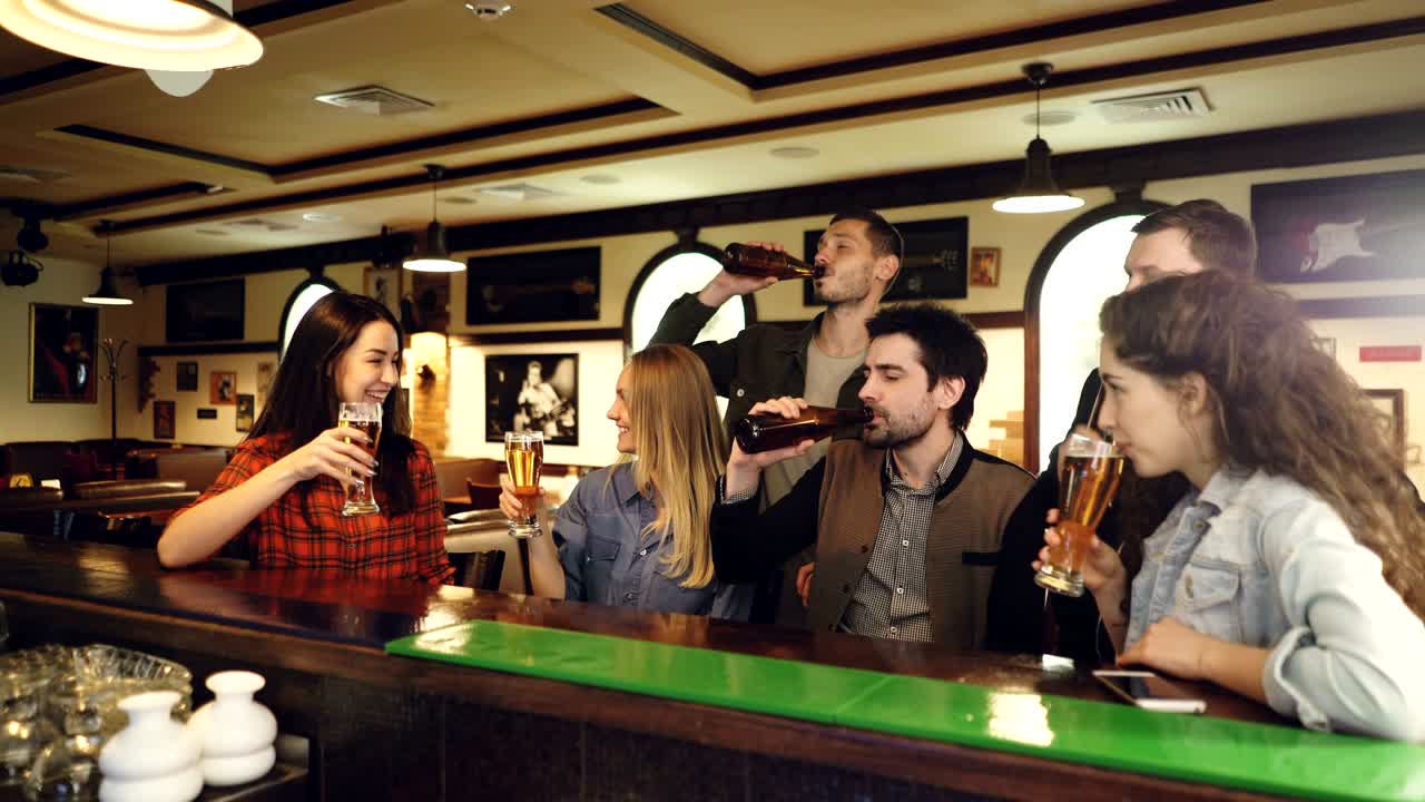 un grupo de amigos con ropa casual están hablando, haciendo sonar vasos y bebiendo mientras se reúnen en el mostrador en un bar de lujo. concepto de celebración de entretenimiento de comunicación.