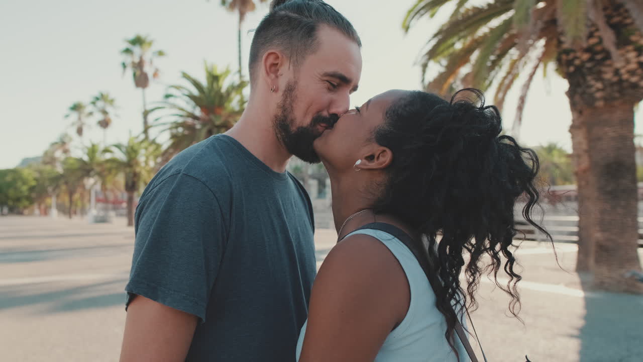 Casal inter-racial trocando um beijo em um ambiente urbano