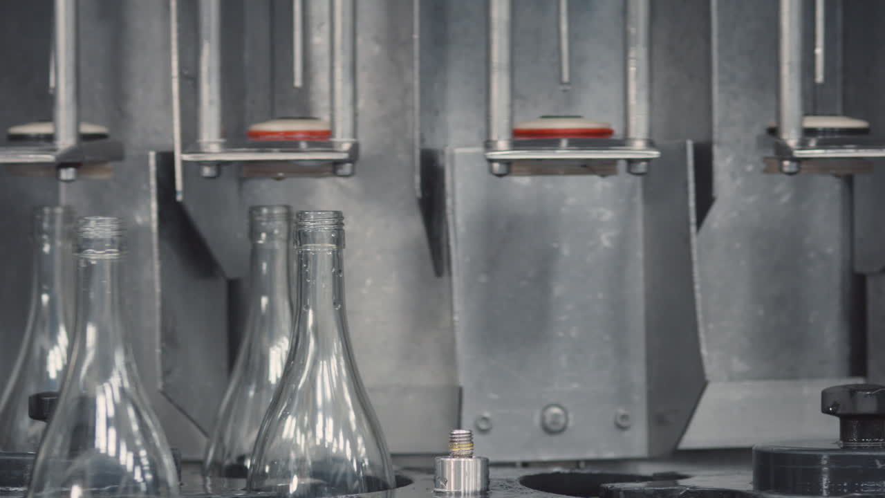 Medium shot showing an organized row of glass bottles in a factory, ready to be filled with wine.