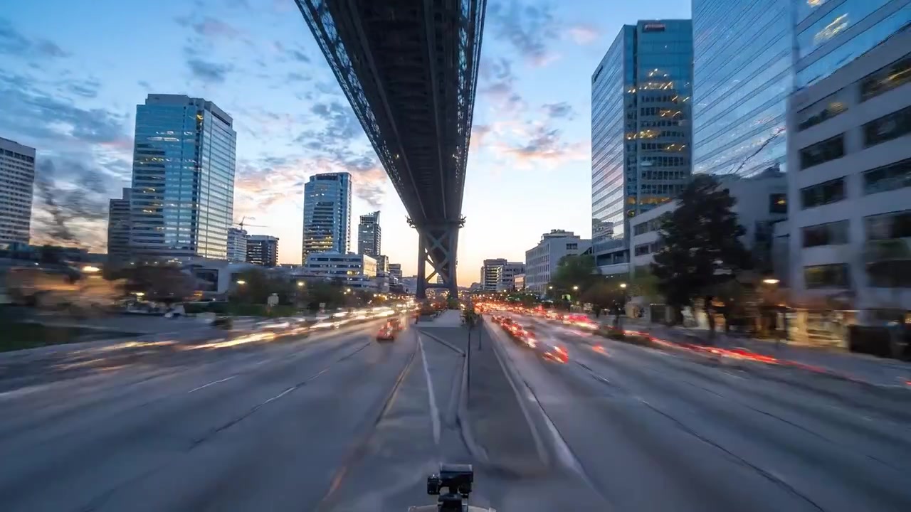 Dynamic Urban Evening Scene Under Bridge with Fast-Moving Traffic and Glowing City Buildings Captured in Two Frames, Transitioning from Dusk to Night.