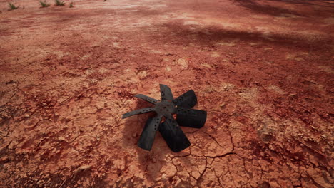 una cuchilla de ventilador oxidada en la tierra roja agrietada